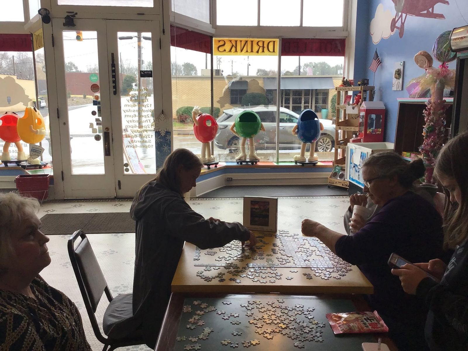 Customers working on a jigsaw puzzle at a table inside The Candy Shoppe on Main